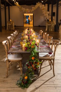 Chic long table we designed for The Knot Market Mixer complete with greenery runner details and gold candle holders 