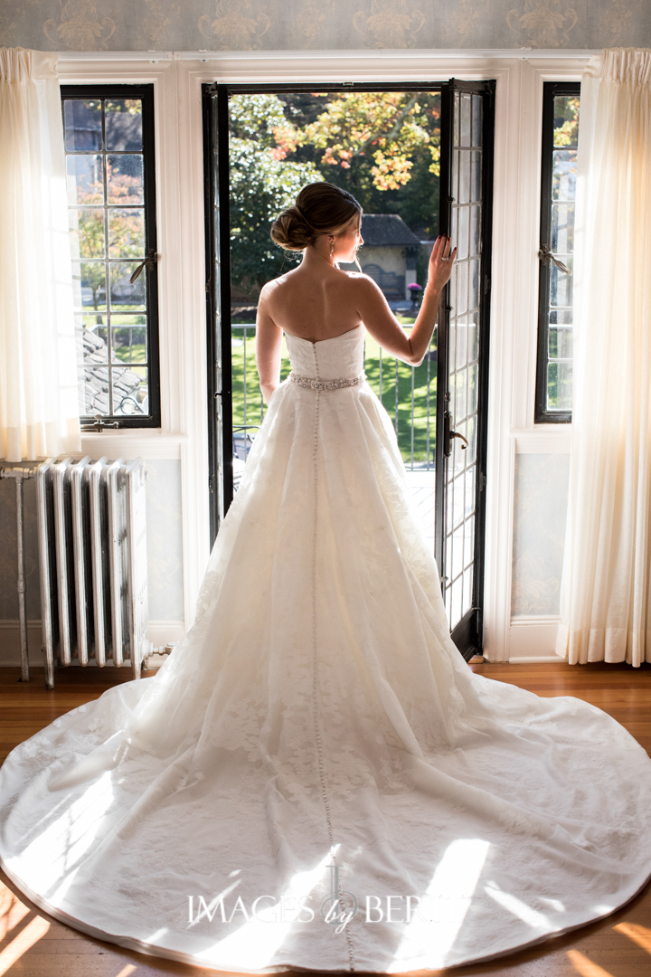 back of bride in dress standing in window