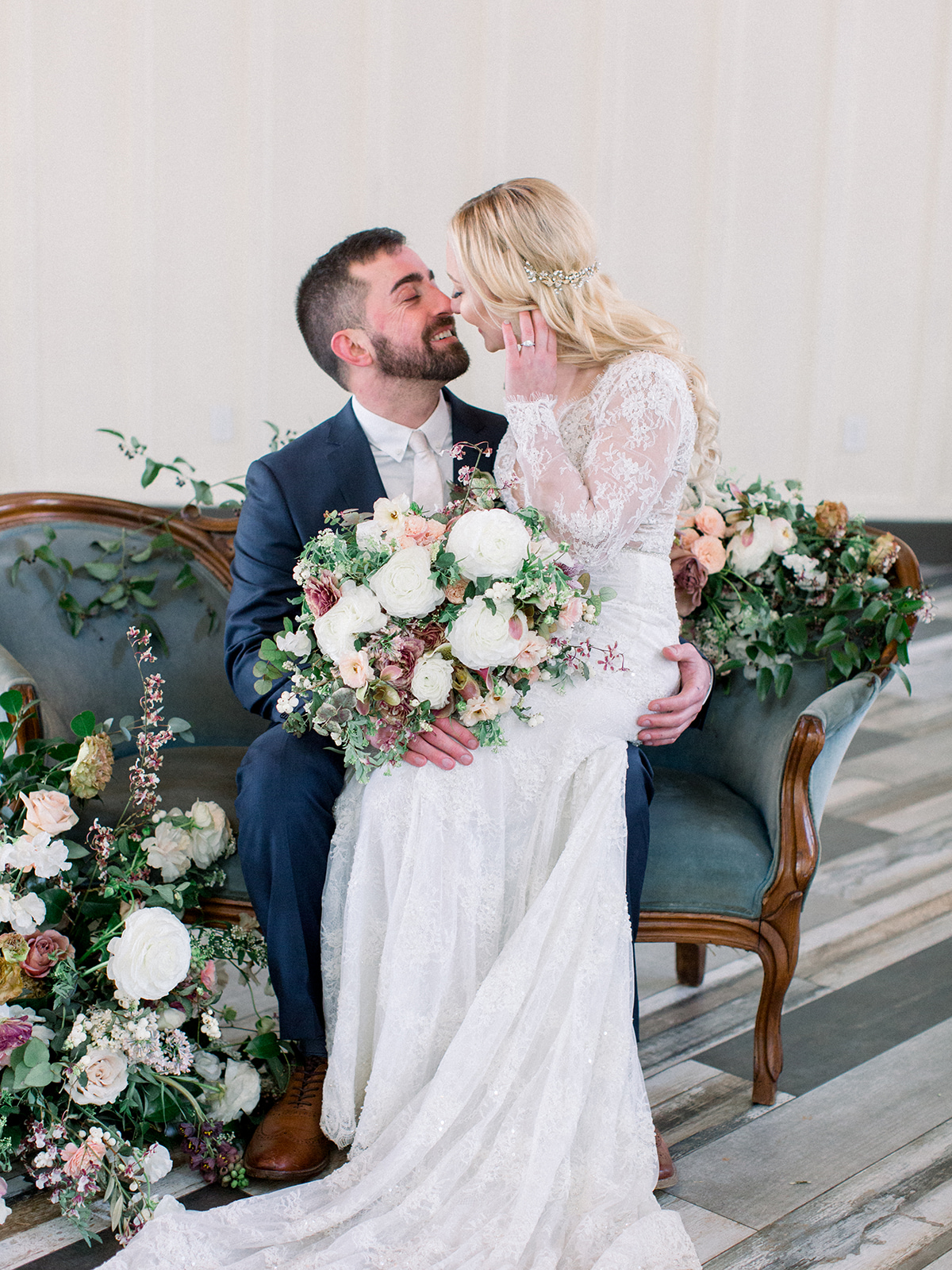 bride sitting on groom's lap on vintage blue couch covered in flowers