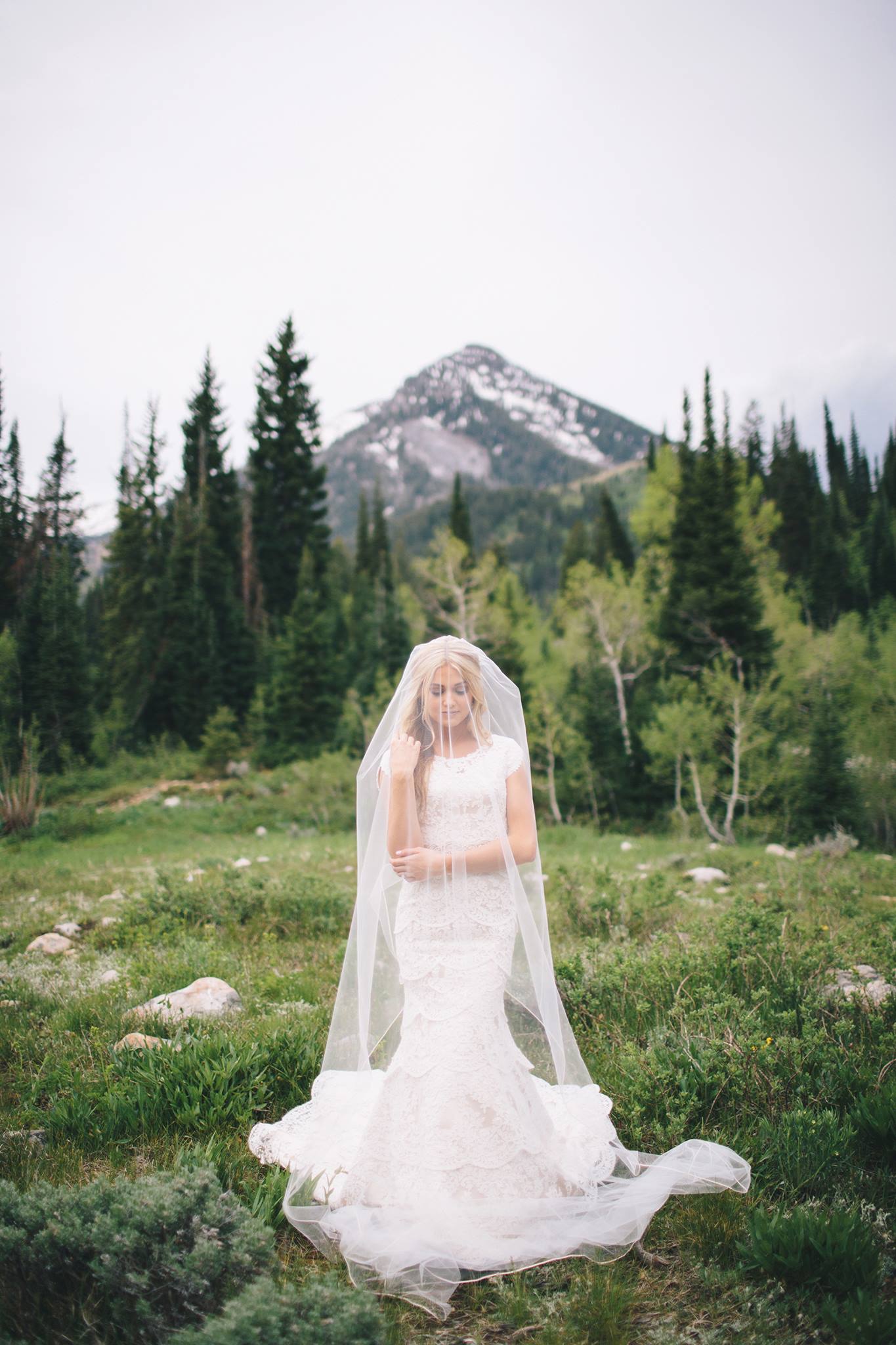 bride with veil covering her face standing in front of a mountain