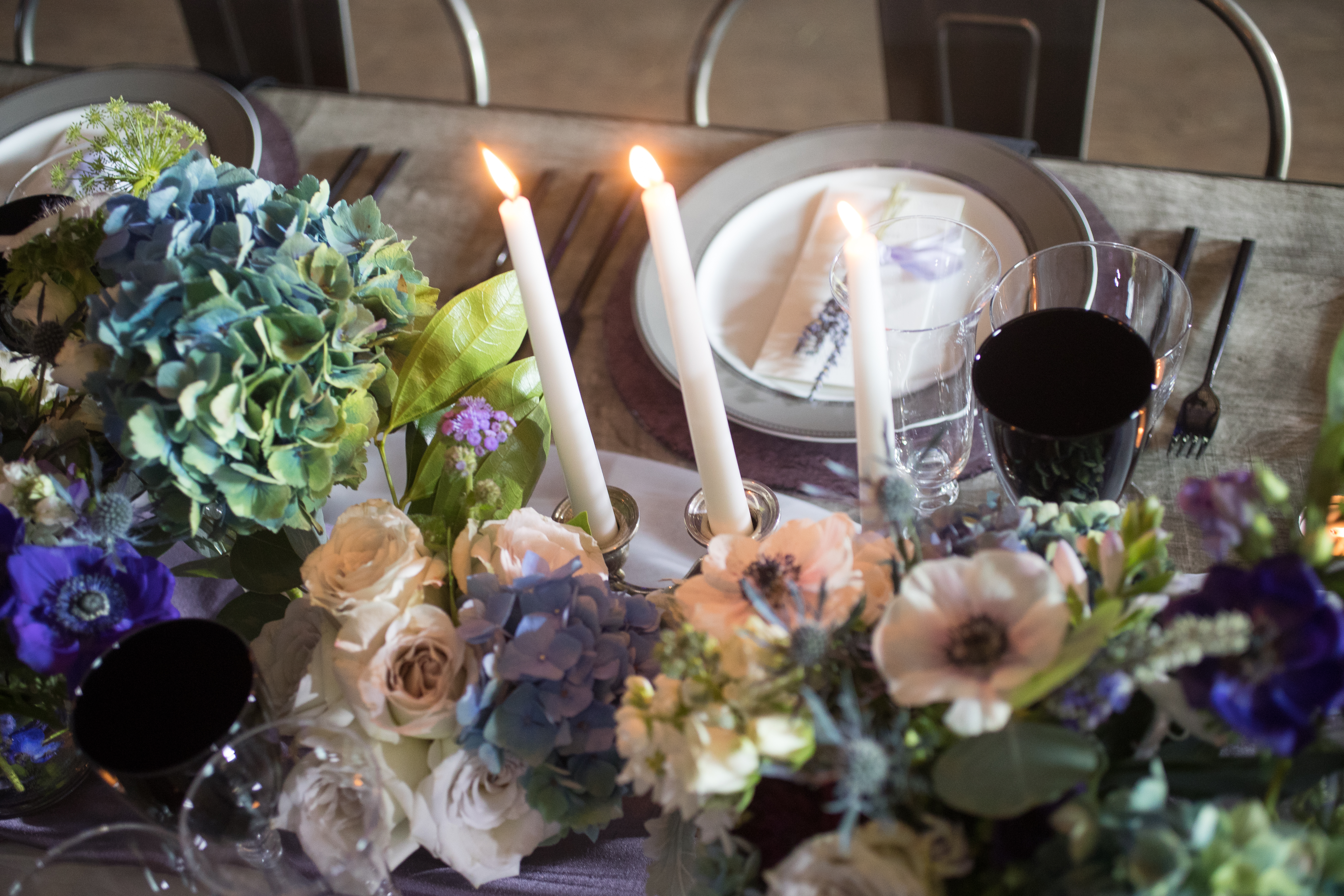 pictures of purple and blue flowers on gray tables with long white candles