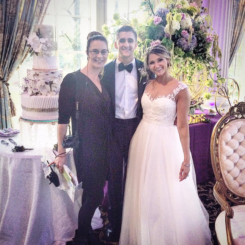 bride and groom with wedding planner in front of wedding cake