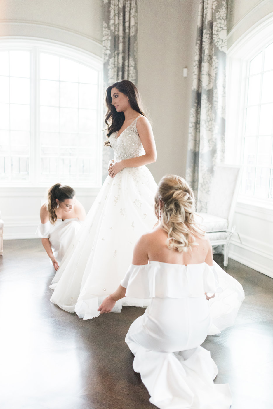 bride in gown being tended to by bridesmaids