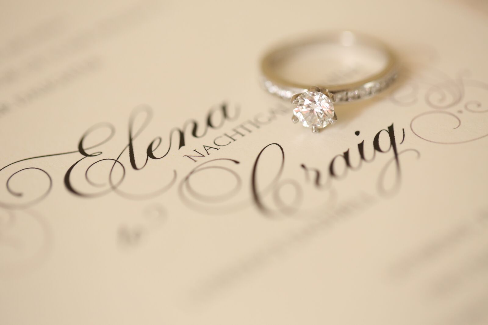 cream colored invitation with diamond solitaire engagement ring