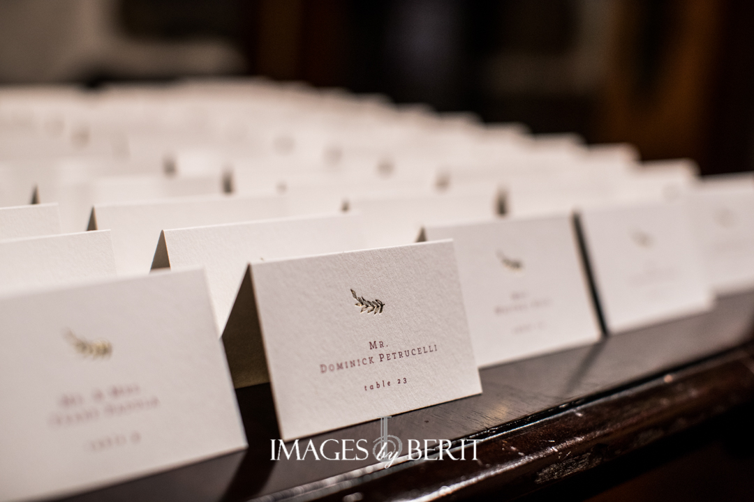 white escort cards with maroon writing and gold leaf detail