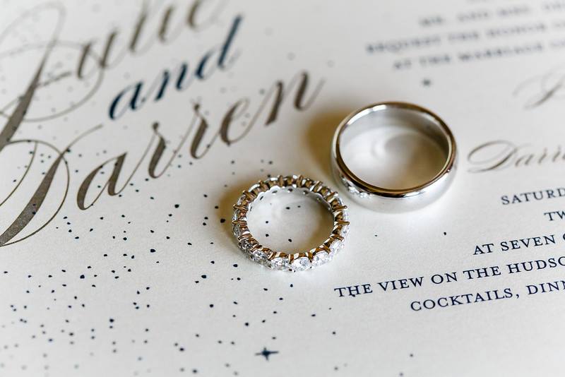 silver and diamond wedding bands on top of sparkly wedding invitation