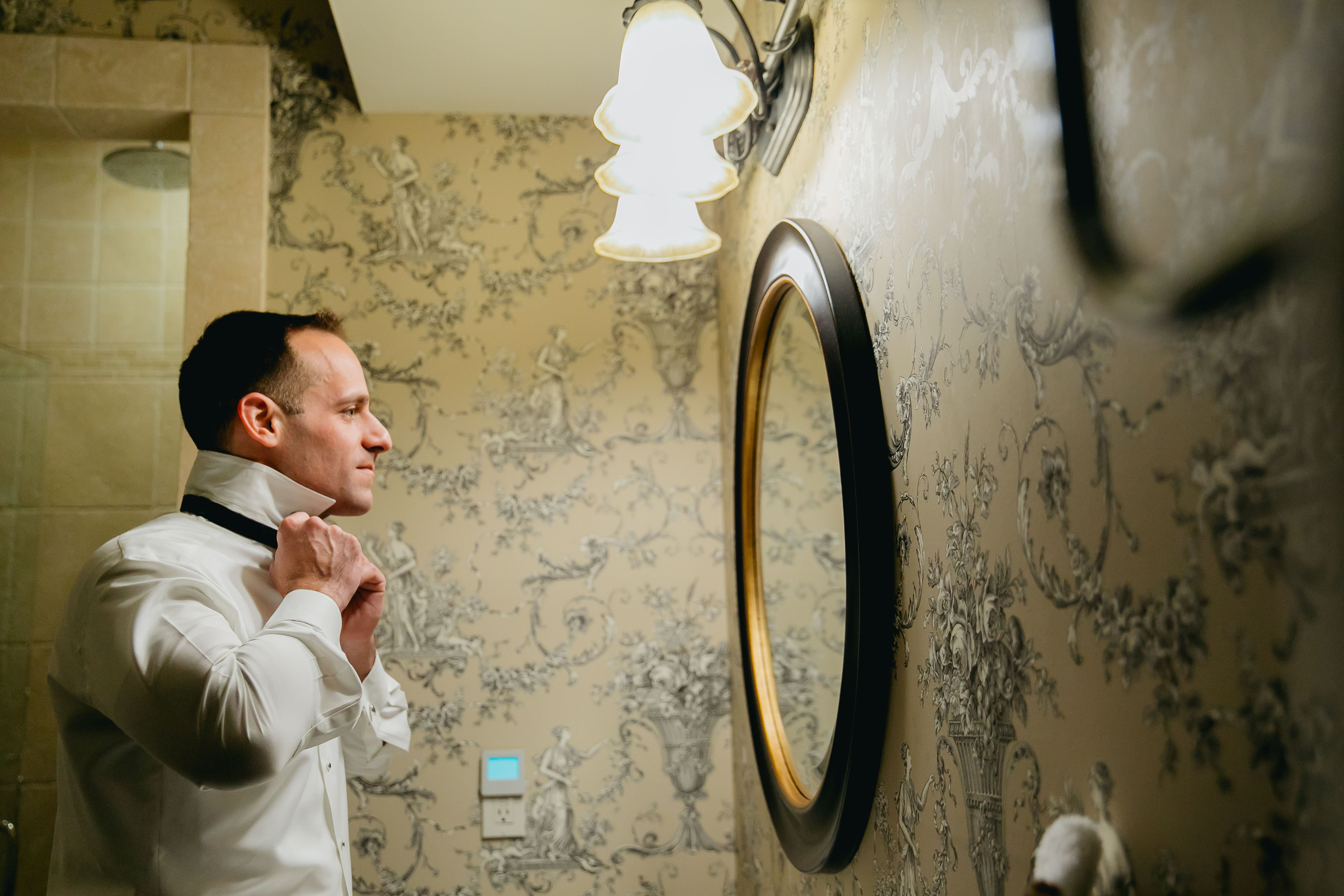 groom adjusting bow tie in mirror