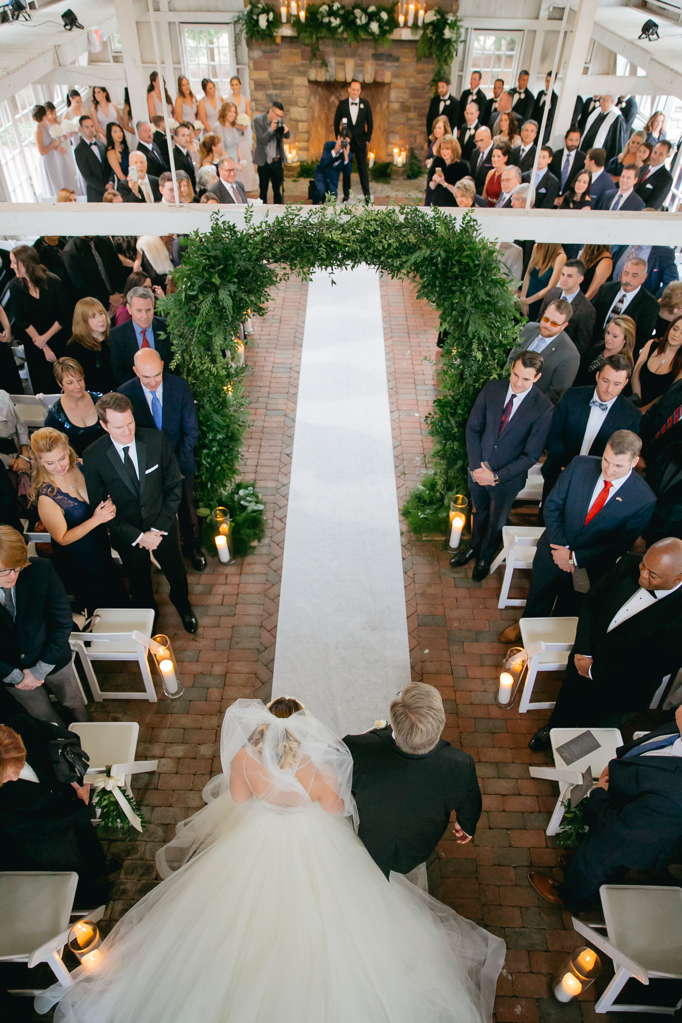 bride walking down the aisle with her dad inside barn