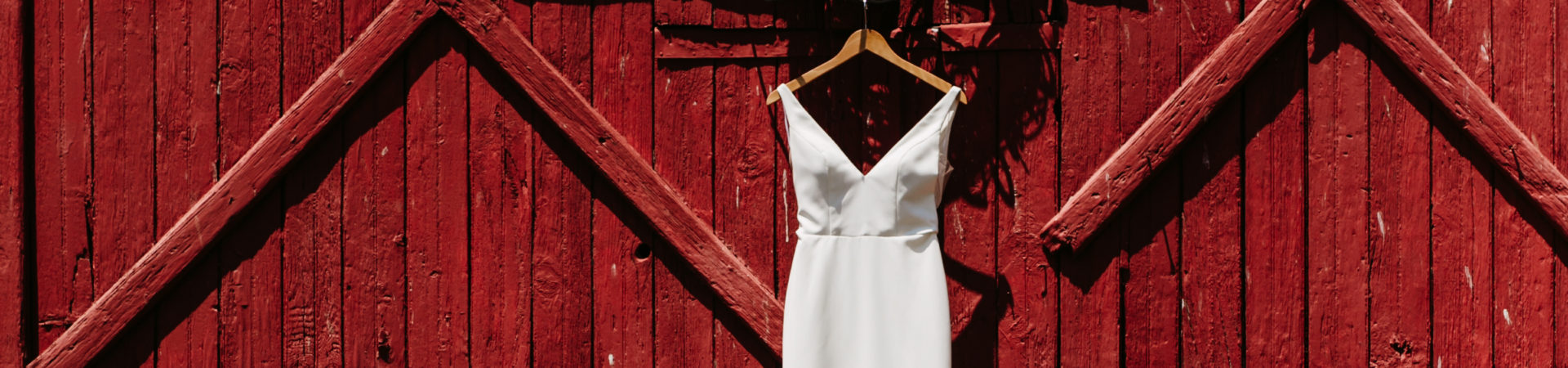 red barn door with hanging white wedding dress