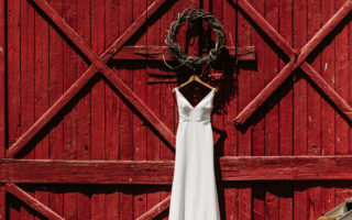 red barn door with hanging white wedding dress