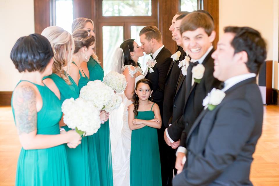 wedding party looking at bride and groom kissing