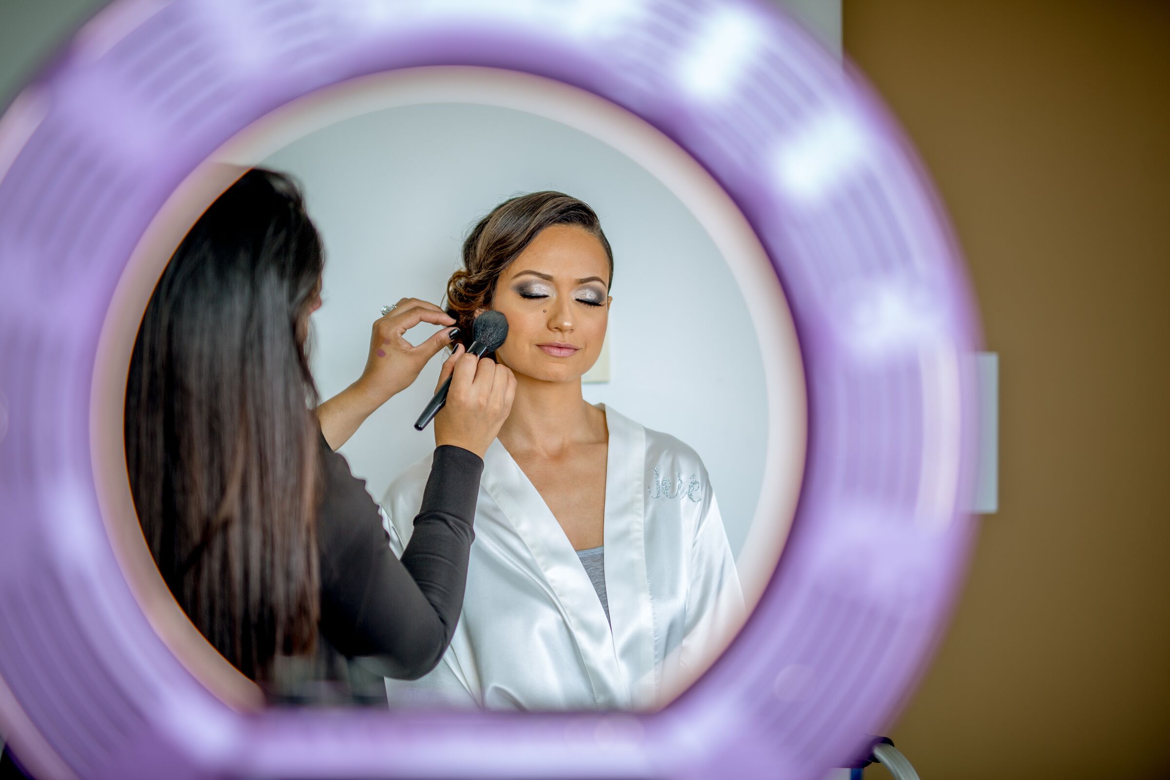 bride getting make up done in mirror