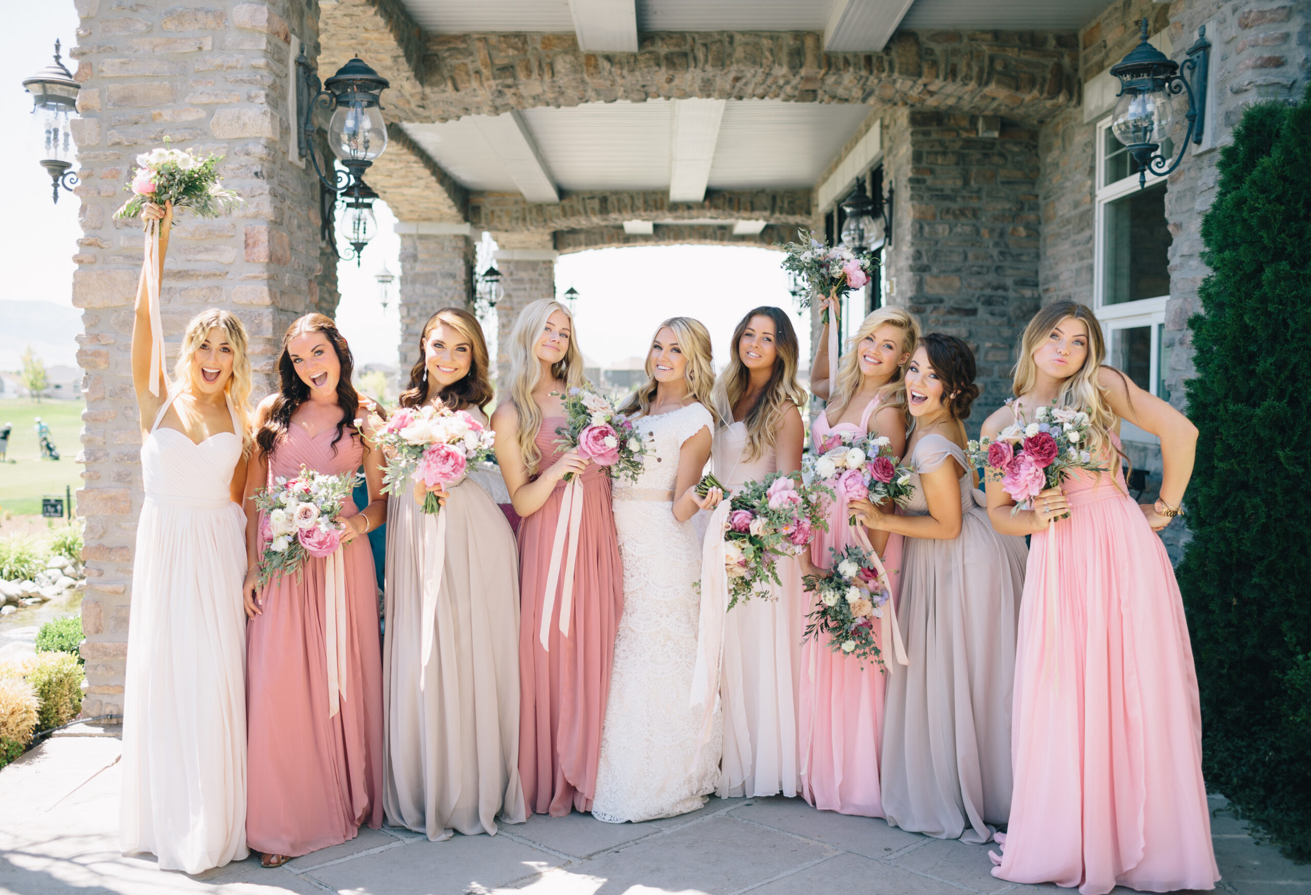 bridesmaids in shades of pink outside with the bride in the middle