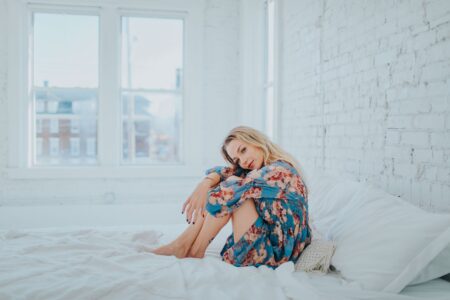woman curled up in white bed