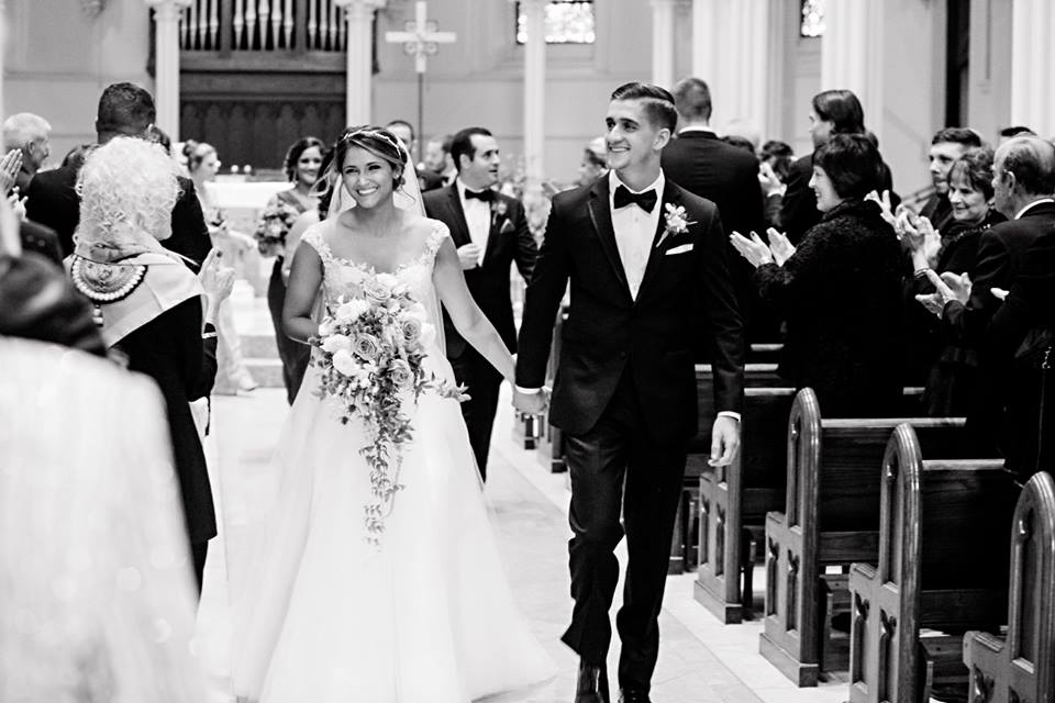 black and white photo of bride and groom walking down aisle