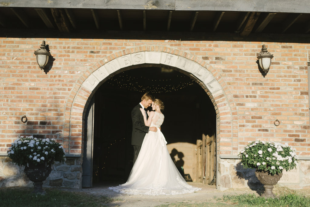 bride and groom embracing brick