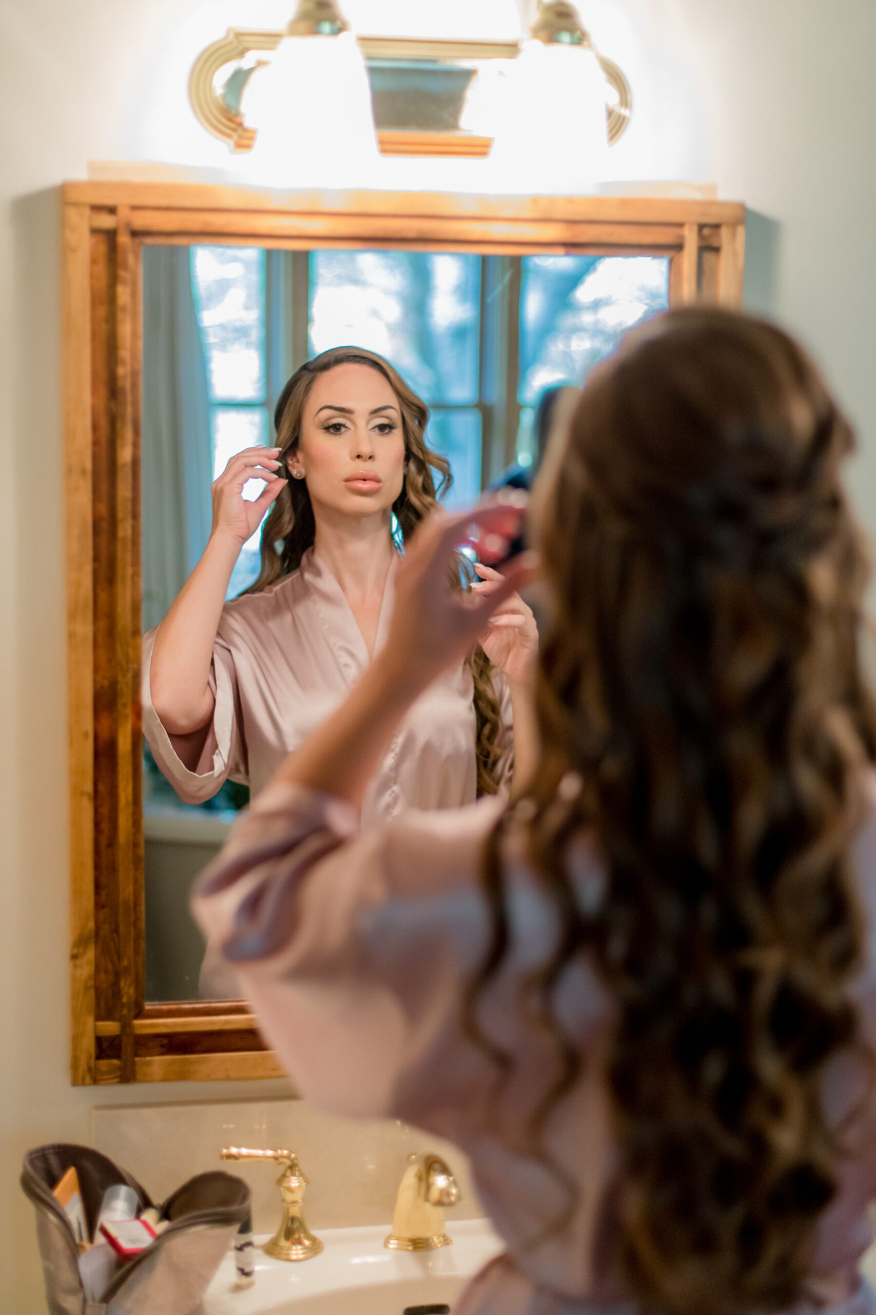 bride getting ready in hair and makeup looking in mirror