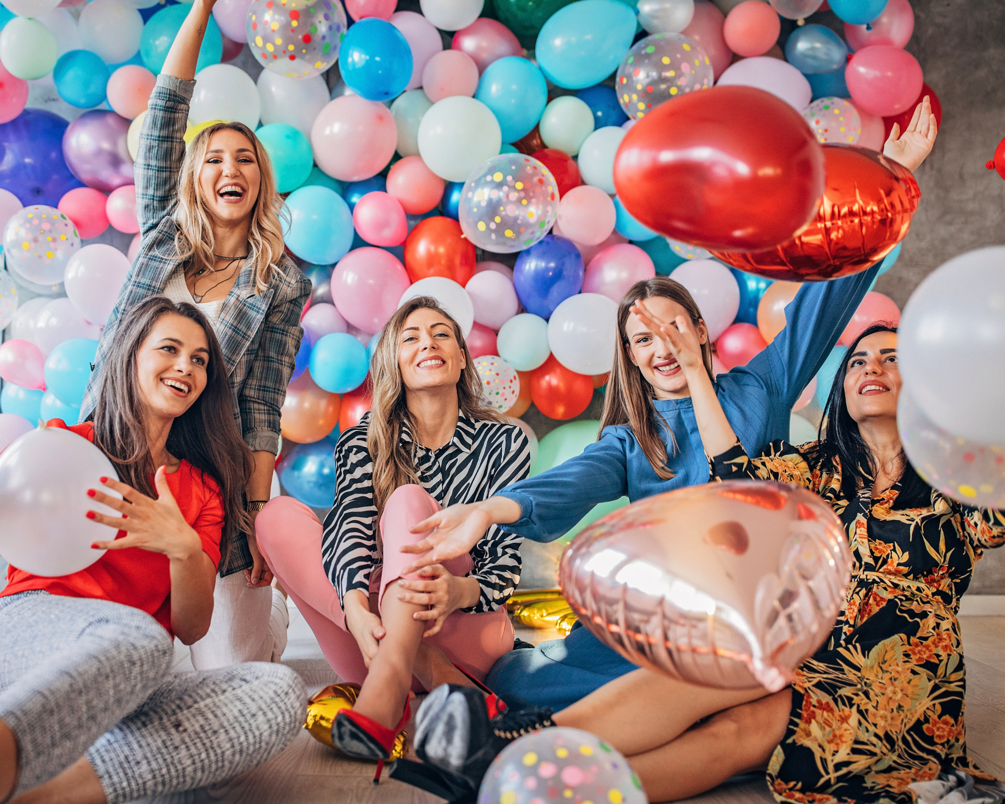 a bunch of girls in front of a balloon wall