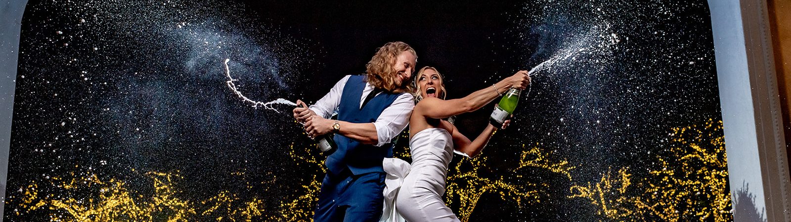 bride and groom popping champagne