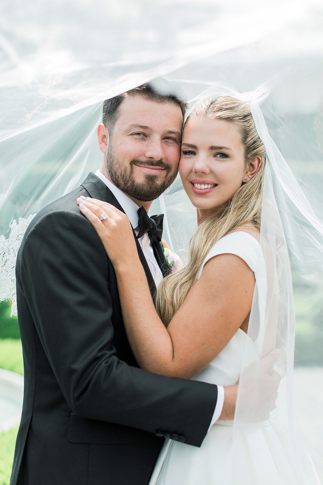 bride and groom under veil smiling
