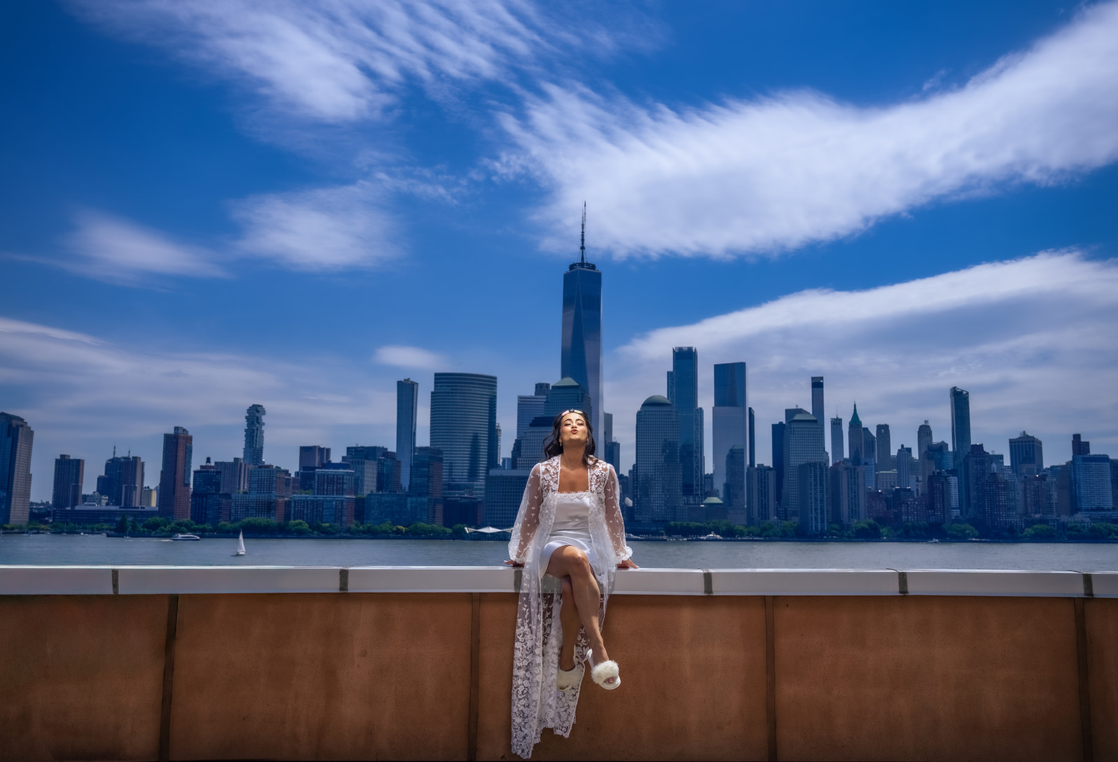 bride sitting on ledge in front of NYC skyline