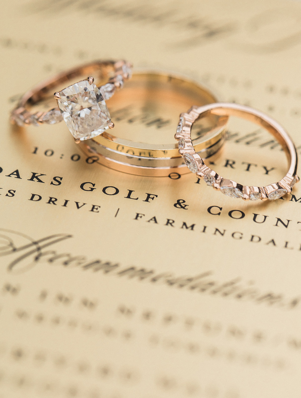 engagement and wedding rings on top of gold invitation