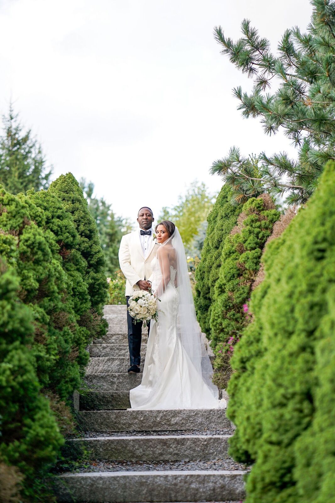 bride and groom standing between trees