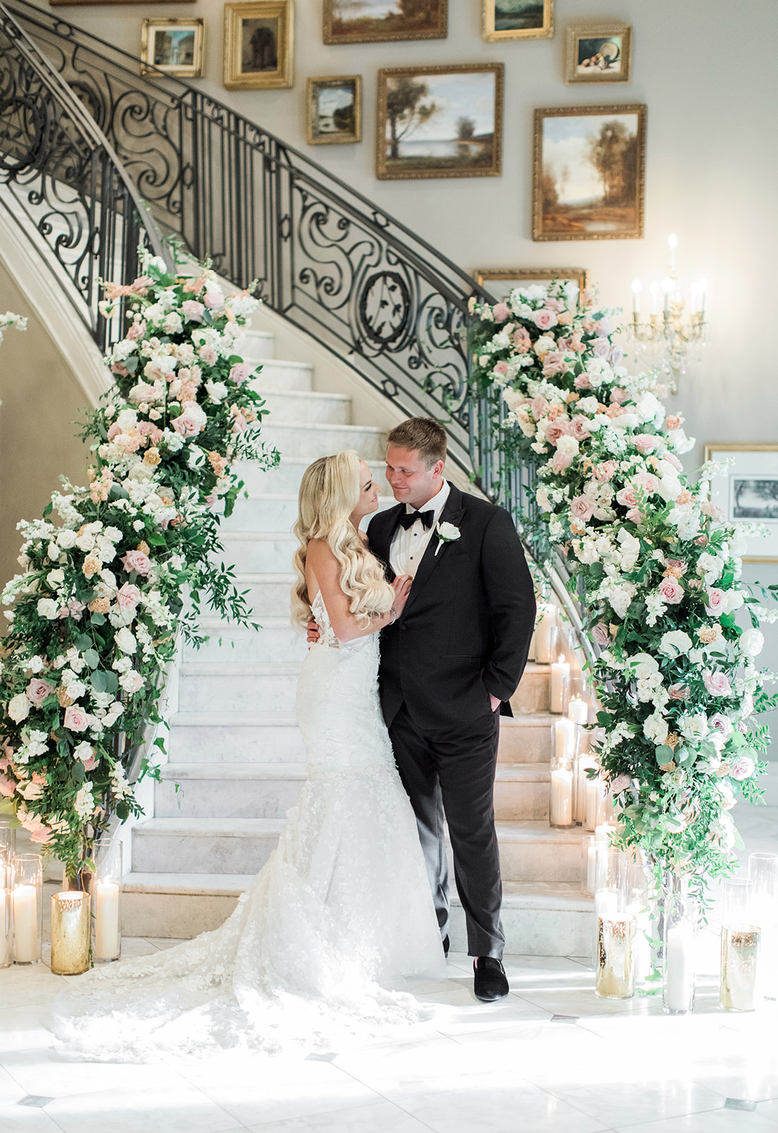 bride and groom standing on staircase filled with flowers